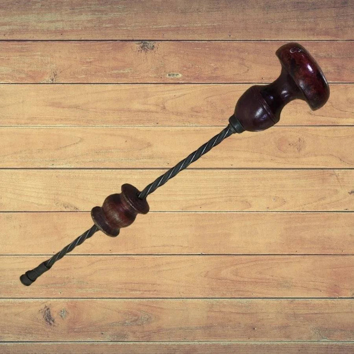 A wooden floor with an antique drill and handle made of wood lying on it.