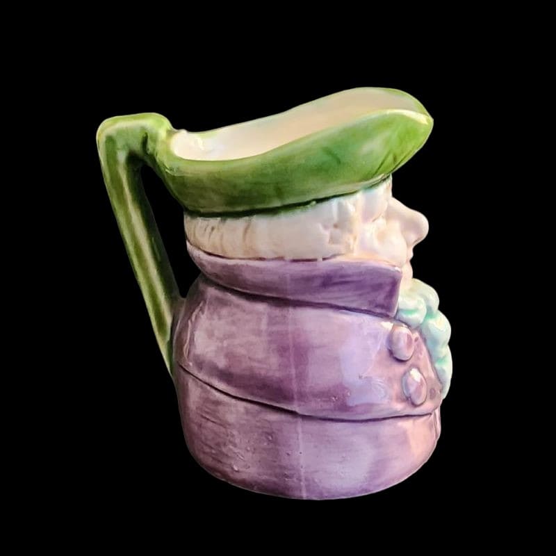 A small porcelain figurine wearing a green hat and a purple coat, showcasing intricate craftsmanship.