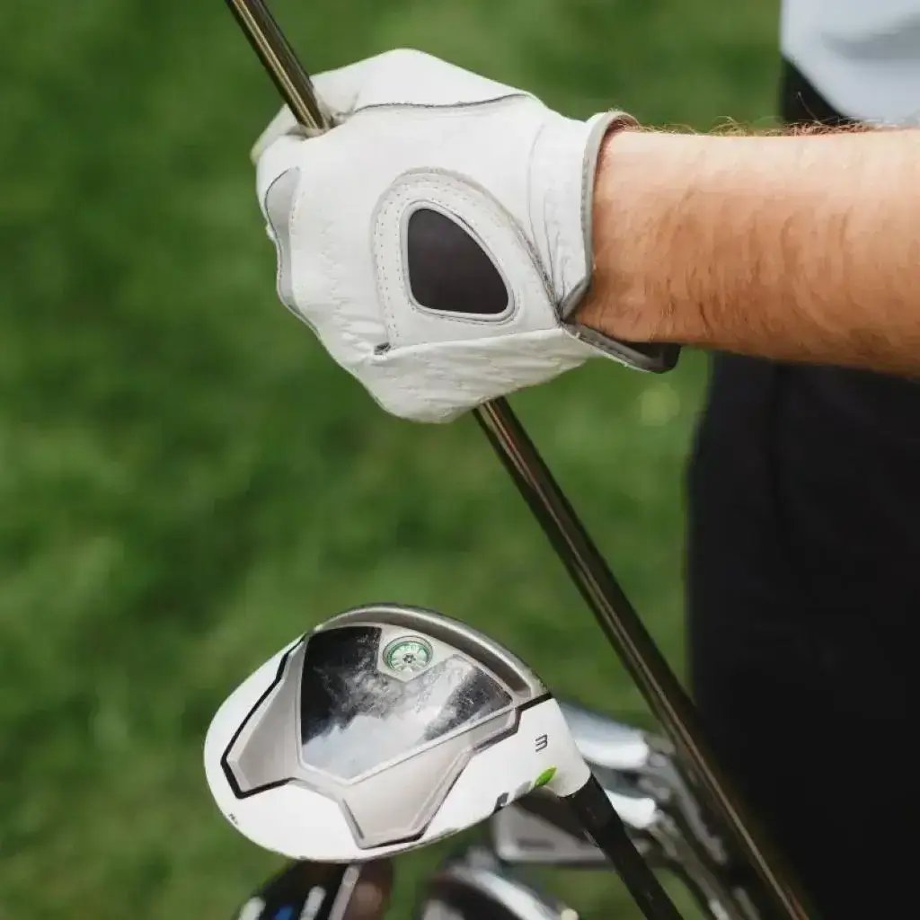 A golfer poised elegantly, gripping a driver, ready to take a swing on a pristine green course.