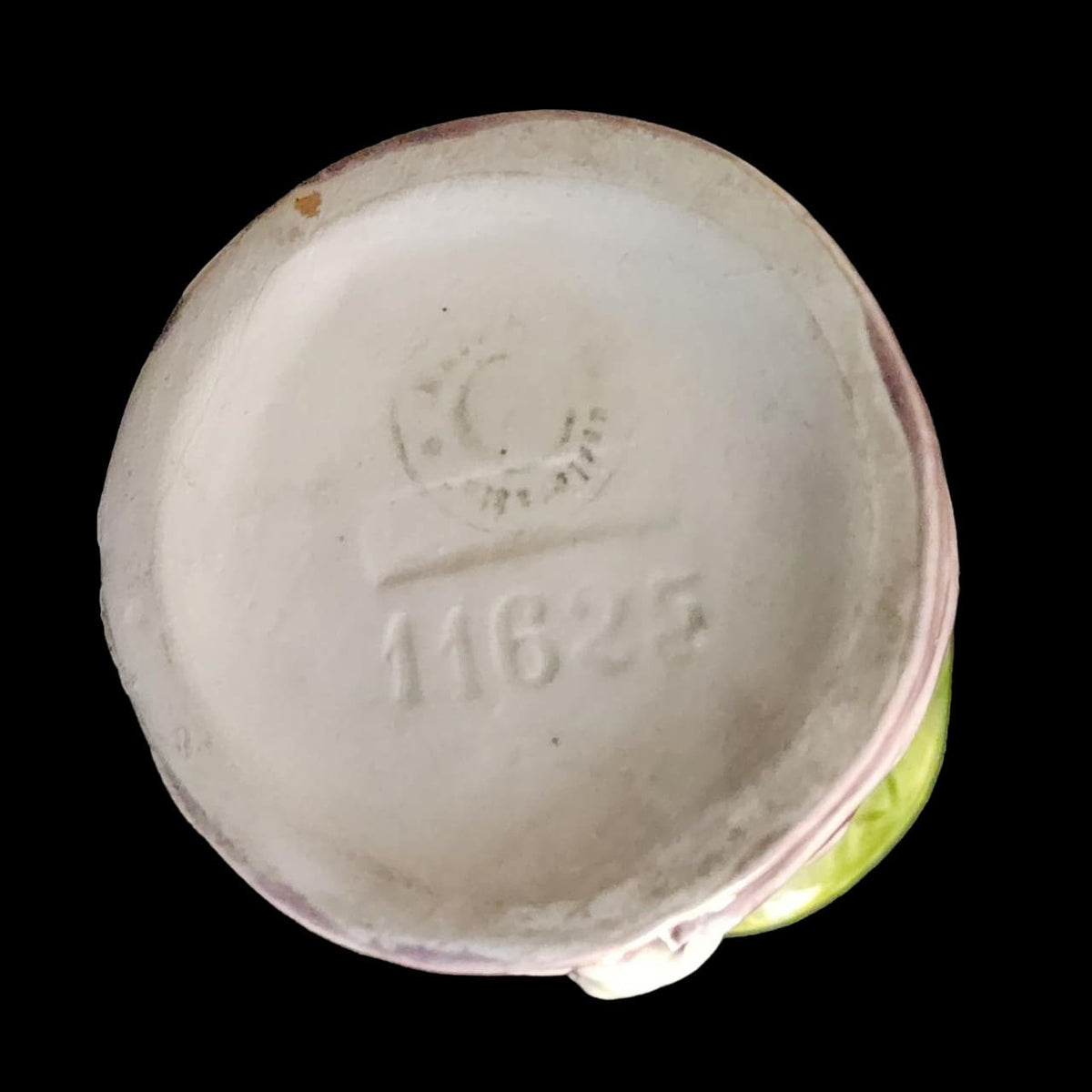 A small porcelain figurine wearing a green hat and a purple coat, showcasing intricate craftsmanship.