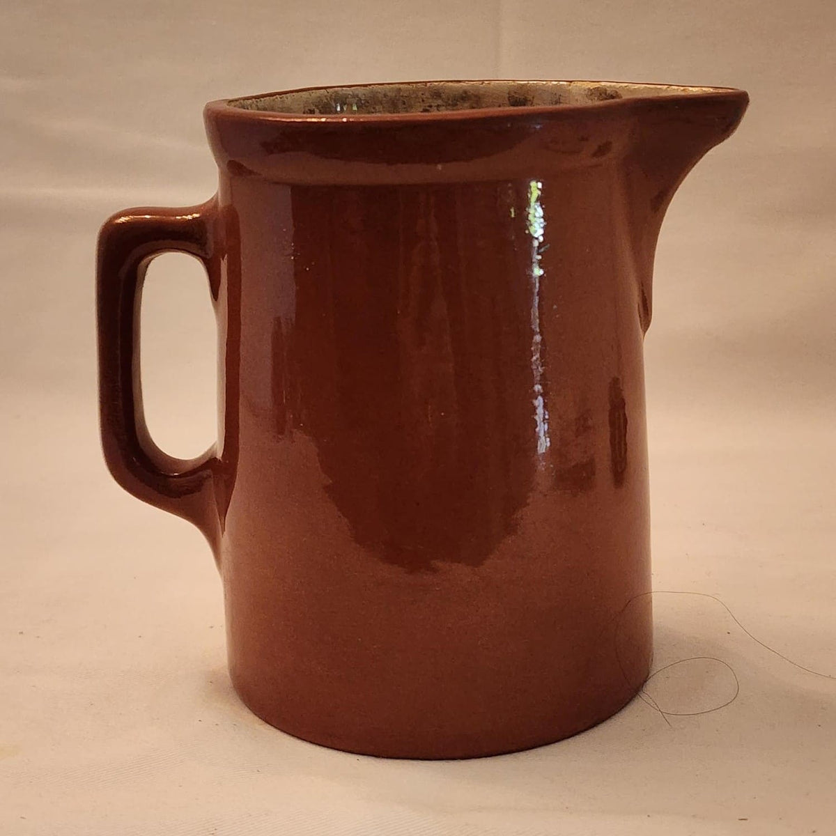 A brown jug with a handle on a white background.